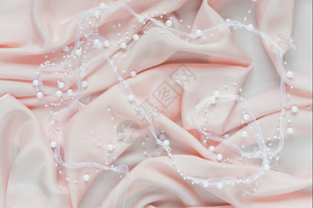 温柔的粉色卷状白丝带和珍珠的婚礼背景图片