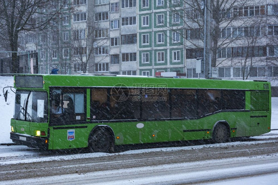 城市公共汽车行驶在被雪覆盖的马路上图片