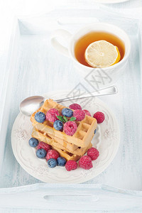 带甜华芙饼浆果和柠檬茶的大陆早餐图片