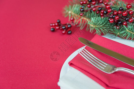 红色餐巾纸上的皮以及色胡利莓和绿树枝上有银刀和叉子它位于一个有文字空间的红色桌布覆盖子上图片