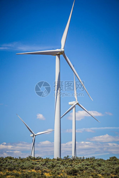 在阳光明媚的风天发电涡轮机图片
