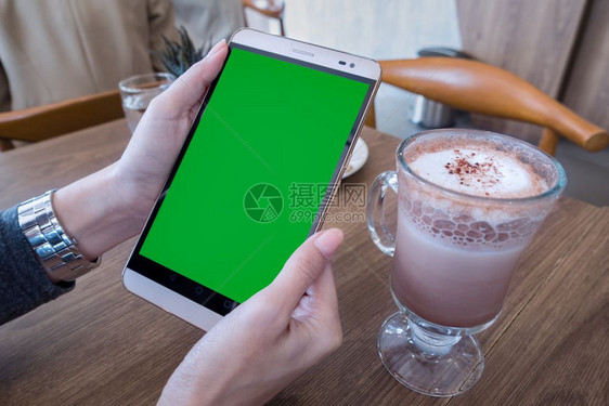 手持机的妇女带有绿色屏幕用于广告短信或宣传内容在咖啡厅用手机阅读新闻图片