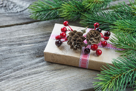 在古旧未涂漆的木板背景上由松锥树枝和礼品盒以及卷锥和胡萝卜果组成的圣诞树构带有复制空间图片