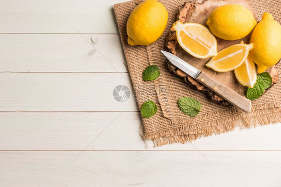 切片半新鲜的多汁柠檬薄荷叶和刀在旧木制桌子上顶部视图与复制空间图片