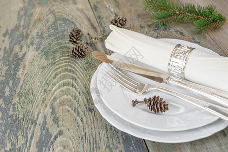 圣诞餐桌银刀叉餐桌巾纸放在白盘上绿色树枝和甜圈放在旧木桌上有文字空间图片