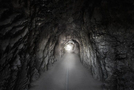 低光照片显示一条路经过座山上建造的隧道墙上有石尽头亮光隧道位于山坡上图片
