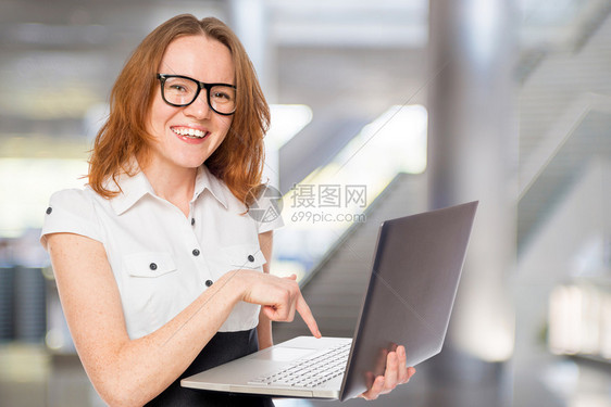 办公室里有台笔记本电脑的一位快乐和成功的女商人肖像图片