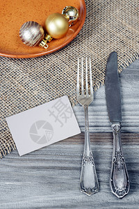 陶瓷板上的铁叉刀和圣诞球都放在粗的木制桌子上面盖着粗的垫子有白纸卡图片