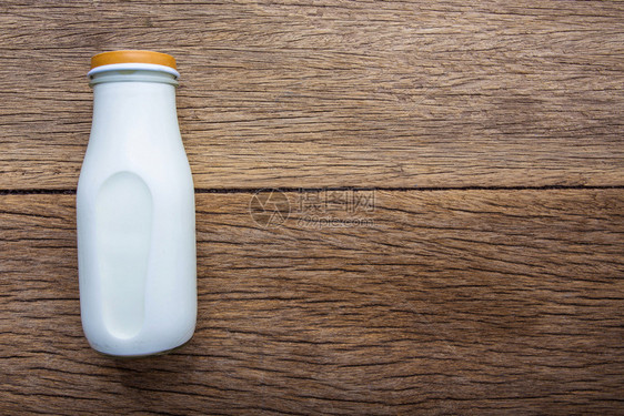 木色背景上的牛奶瓶俯视图图片