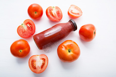 瓶装鲜番茄汁和白木底的鲜番茄片图片
