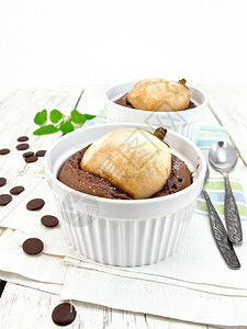 2个白碗甜点巧克力和梨子勺餐巾上的薄荷放在背景浅木板上的厨房毛巾图片
