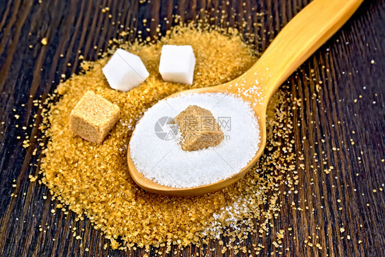 立方体中的糖棕色和白在木板底部的勺子中颗粒图片