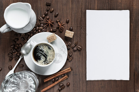咖啡杯牛奶罐中的霜水杯白纸卡和木桌上各种香料及复印空间顶视图片