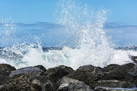 潮汐波在海岸的岩石上被击碎成小的浪花图片