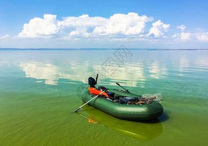 在阳光明媚的天气中在平静的河流中有充气的船橡胶孤单船在阳光阴云的天气中有充的橡皮船图片