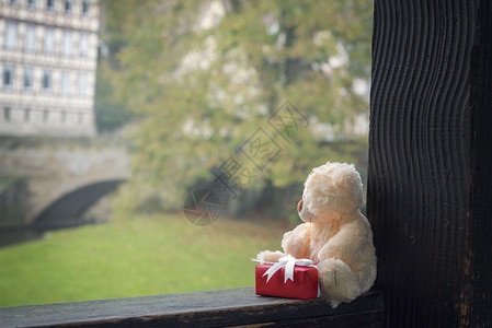 装满熊玩具和带白丝的红色礼物盒坐在木束上图片