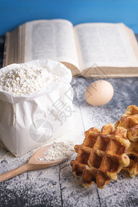 一袋面粉木勺鸡蛋比利时华夫饼和一本开放的书图片