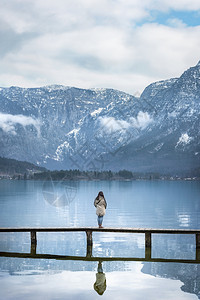 欧洲旅行地点的图像一个女人站在甲板上欣赏austrinlps山的景象反映在austri的大厅湖图片