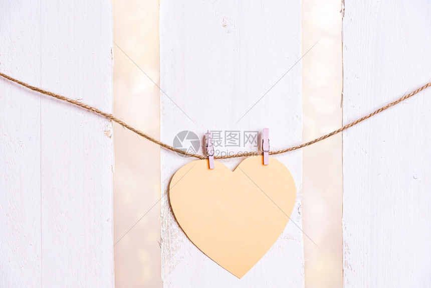 浪漫的画面黄色心形纸条绑在绳子上面有两根木制剪片白色的木制栅栏背景图片