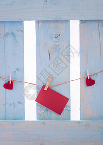 红色的纸条被心包围绑在有木片的线条上在蓝色的栅栏上图片