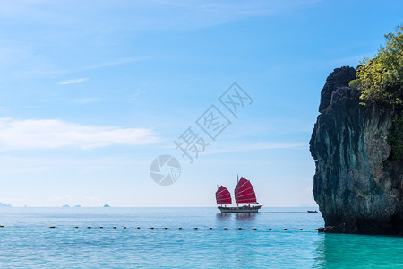 在阳光明媚的一天在安达曼海中乘着红帆的游艇图片