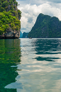 垂直照片一个图片库在岩石附近的海域看到一条传统的泰河船图片