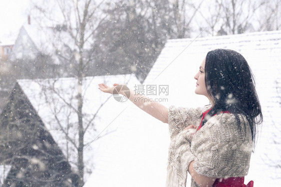 身着红裙子的黑发年轻女人手抓雪花图片