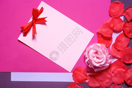 用红弓的粉色纸条的贺卡想法四周都是用肥皂洋红和紫色纸底画成的玫瑰和红花瓣图片