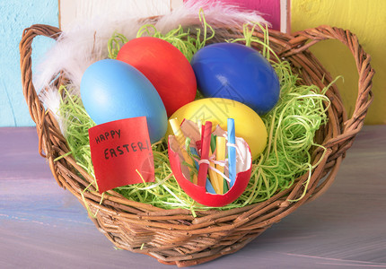 满是彩蛋和滚纸条的壳和充满欢乐的复活节词圆篮子以多彩的木制背景图片