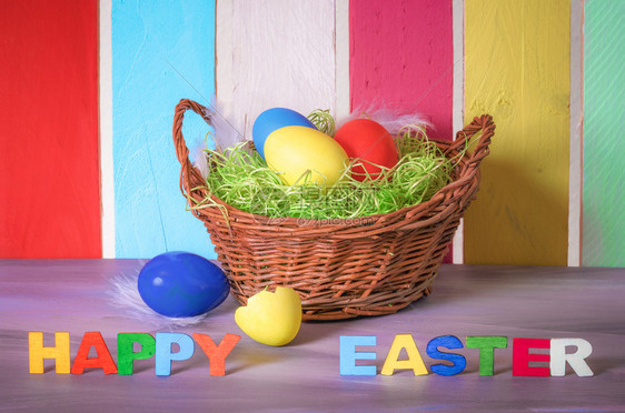 装饰鸡蛋篮和复活节快乐的词写着多彩木字和背景上多彩的栅栏图片