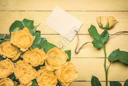 带玫瑰花束和一朵的贺卡插件上面有一张空白的贺卡上面有一张单线条挂在黄色木制桌子上图片
