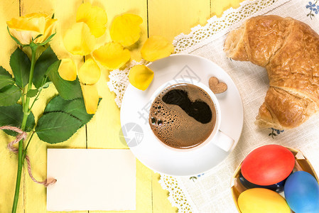 早餐桌加一杯咖啡新鲜面包彩色东边鸡蛋和一朵黄玫瑰花瓣落下的和一张贺卡图片