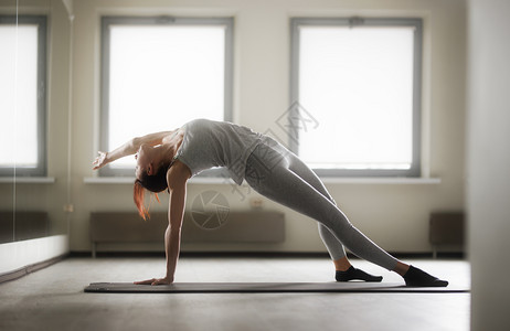 参加瑜伽锻炼的年轻运动妇女坐在明窗附近的健身房里图片