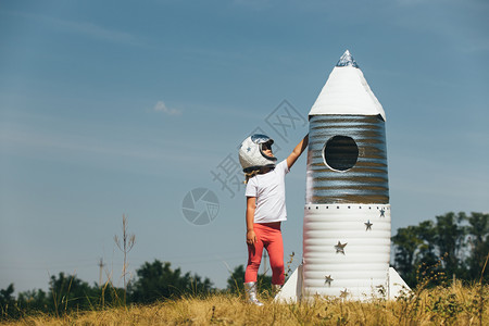 身着宇航员服装的快乐女孩玩着手制火箭夏天户外快乐女孩穿着宇航员服装的快乐女孩玩着手制火箭图片
