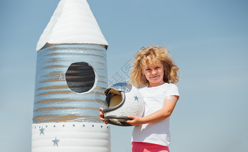 身着宇航员服装的快乐女孩玩着手制火箭夏天户外快乐女孩穿着宇航员服装的快乐女孩玩着手制火箭图片