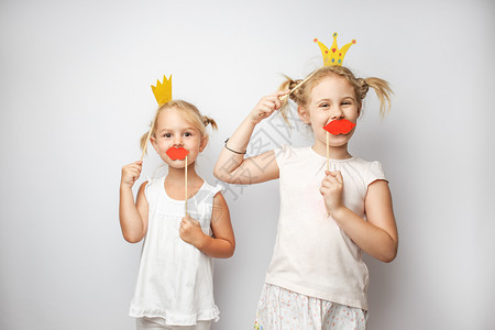 两个可爱的小女孩双可爱的小女孩双纸冠和红嘴唇在家中装白色背景双纸冠和红嘴唇装白色图片