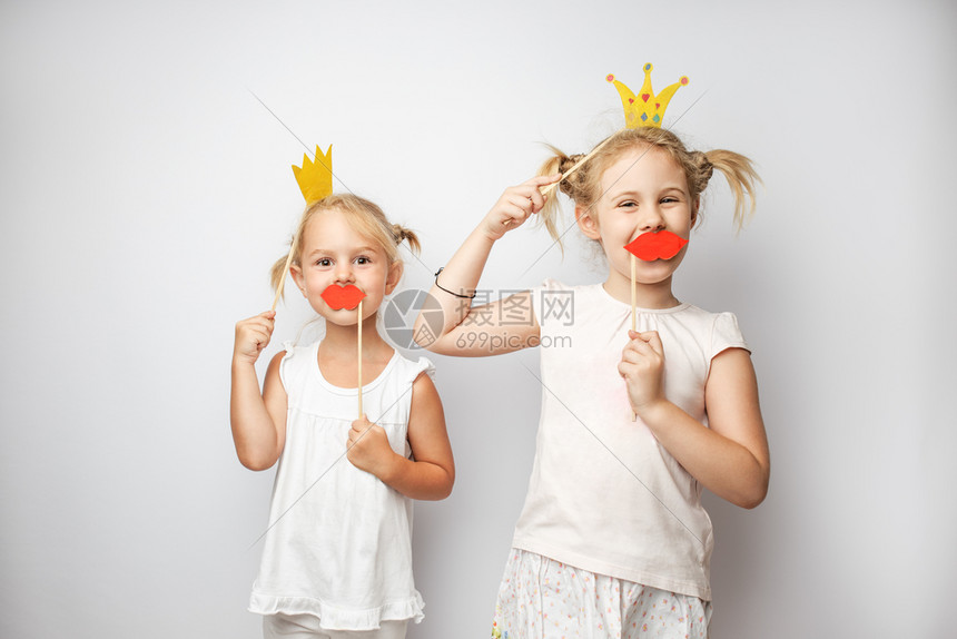 两个可爱的小女孩双可爱的小女孩双纸冠和红嘴唇在家中装白色背景双纸冠和红嘴唇装白色图片