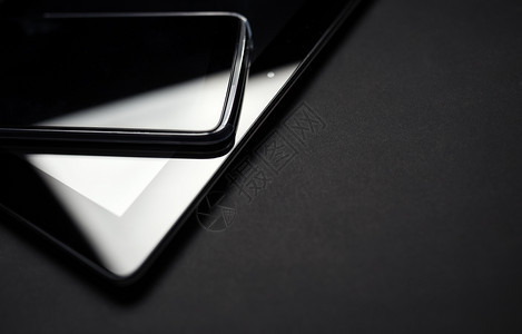 在平板电脑上倾斜的智能手机关闭照片黑色背景的电子设备图片