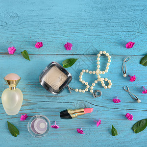 蓝色木背景上的珍珠项链和化妆品图片