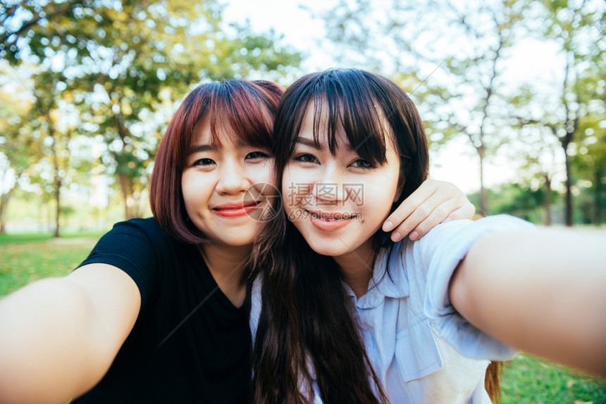 两个快乐的年轻亚洲女朋友一起在公园玩乐个自拍快乐的年轻亚洲女孩