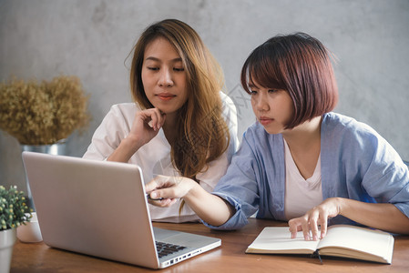 两名青年商业妇女坐在咖啡馆的桌子上使用笔记本电脑和咖啡杯的亚洲妇女在咖啡店工作的自由职业者在办公室以外工作的生活习惯一对的会议图片