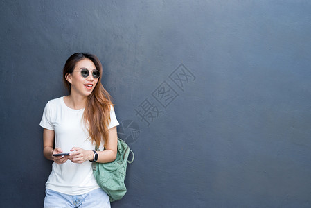 穿着灰墙背景旅行和眼镜风格的感年轻少女户外生活方式肖像图片