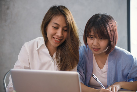 两名青年商业妇女坐在咖啡馆的桌子上使用笔记本电脑和咖啡杯的亚洲妇女在咖啡店工作的自由职业者在办公室以外工作的生活习惯一对的会议图片