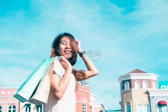 年轻女微笑手里拿着彩色的袋子户外购物概念图片