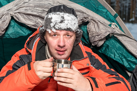 一个冰冻的男子肖像雪在帽子上热茶露营图片
