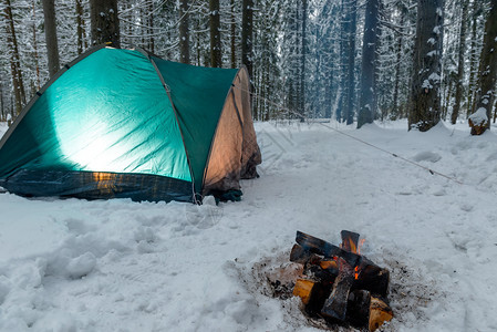 冬天森林的帐篷里有灯光附近的火正在燃烧没有人图片
