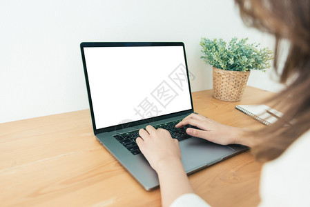 在家办公室工作时使用笔记本电脑并空白屏幕打字在家通过便携式计算机工作的商业妇女在家享受时间图片