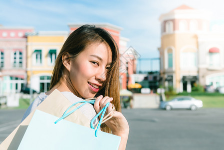年轻女微笑手里拿着彩色的袋子户外购物概念图片