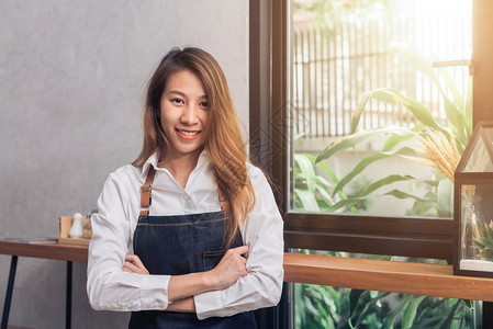 年轻的女咖啡师在她小店里微笑食物和饮料的概念图片