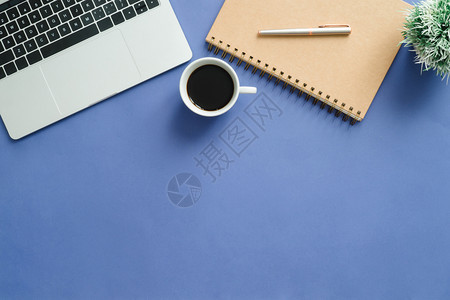 最小工作空间工作空间台的创造平板面照片顶层办公桌有笔记本电脑和蓝色背景的咖啡杯顶层视图有复制空间平面摄影图片